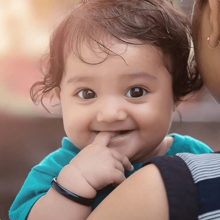 Indian smiling baby on his mother’s arm