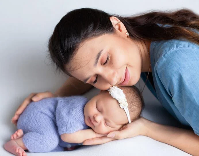 A mother holding her smiling cute baby with her left hand on the baby’s head