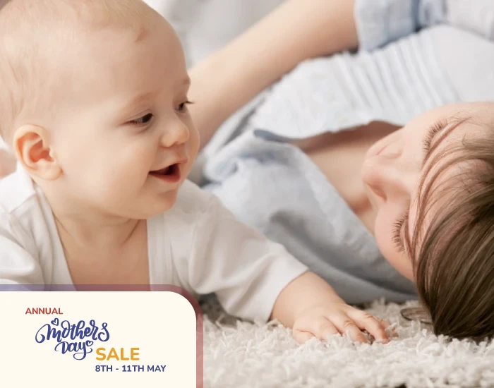 A Mother lying on a carpet playing with her crawling baby