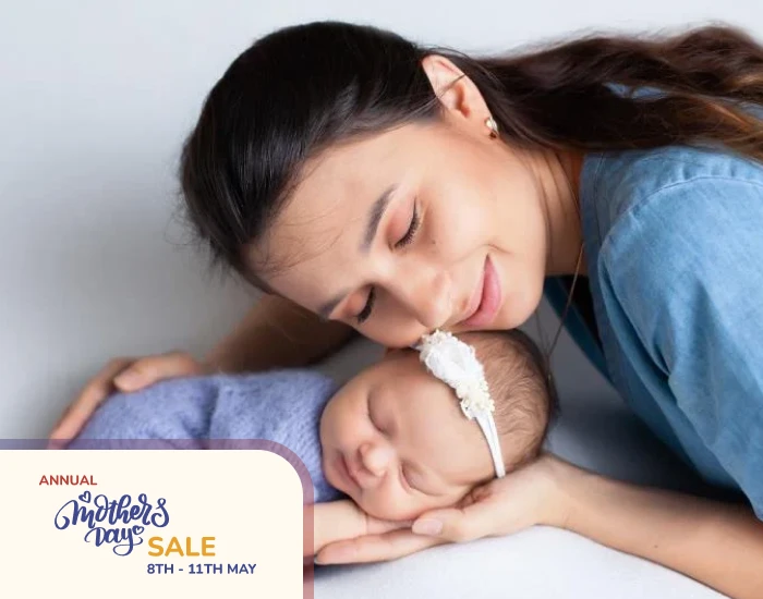 A mother holding her smiling cute baby with her left hand on the baby’s head
